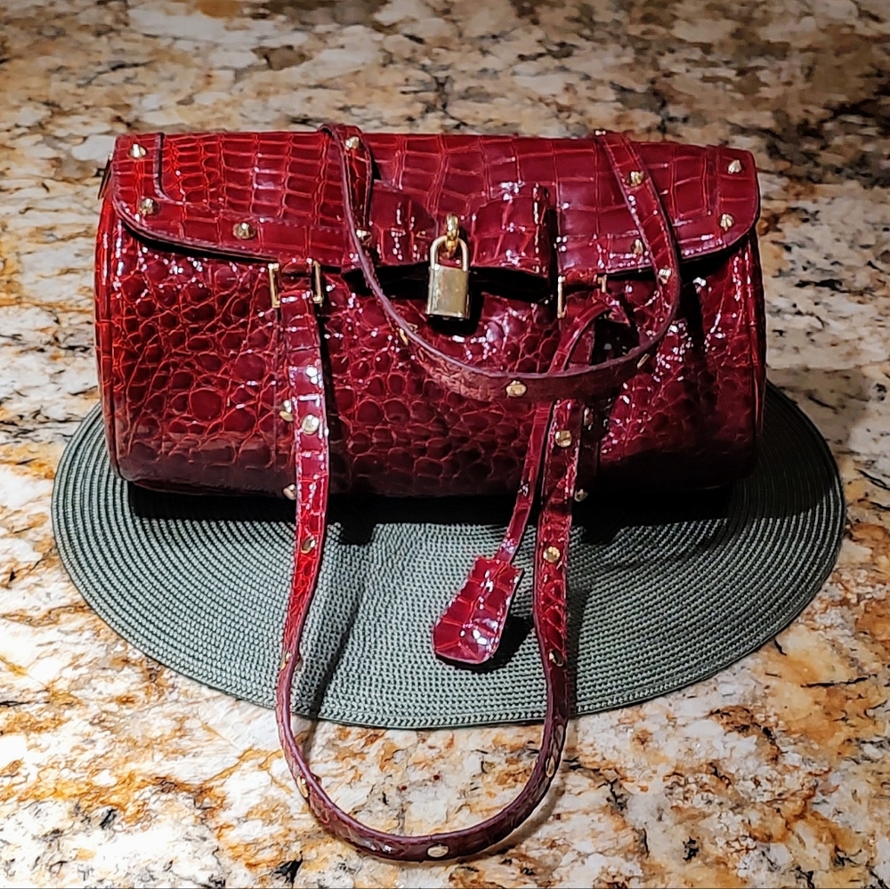 Red/ burgundy croc style bag with gold tone studs, lock and key. Pre-owned.